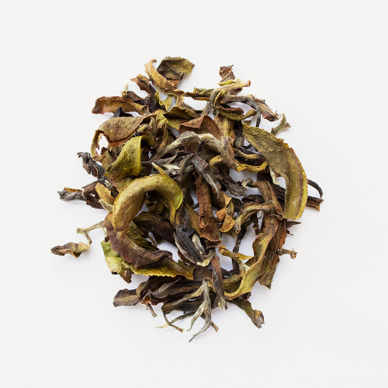 A fragrant pile of Eastern Beauty dried leaves on a white surface from Rishi Tea & Botanicals.