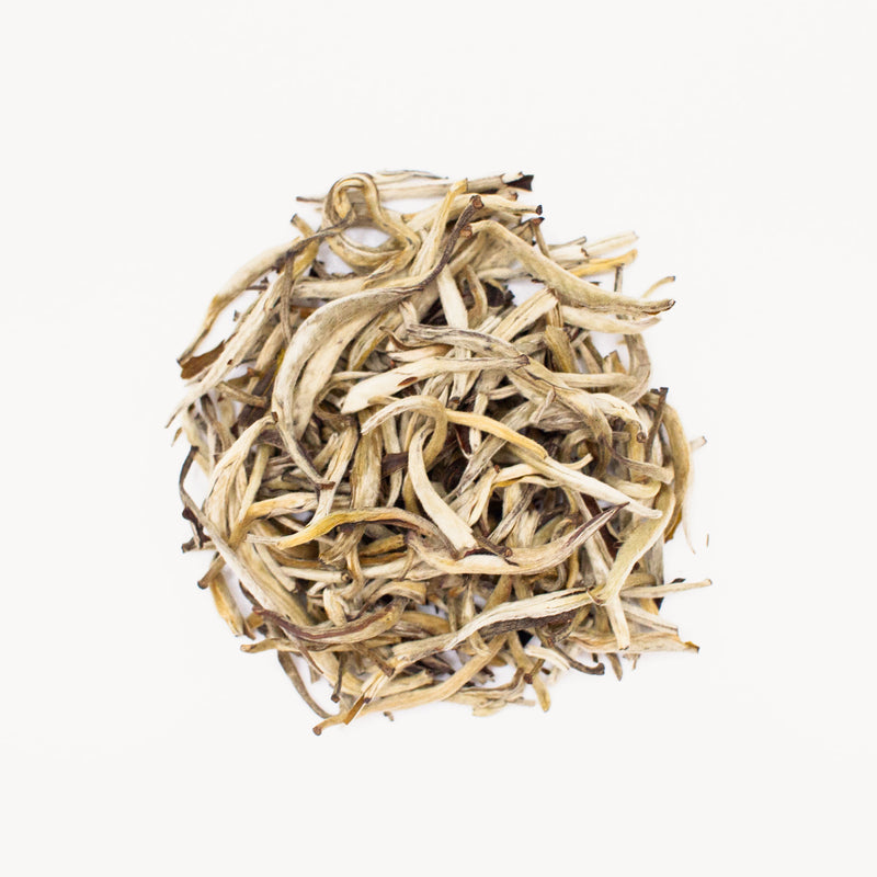 A pile of Rose Scented Silver Needle leaves with a subtle aroma on a white background.