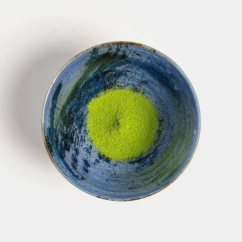 A bowl of green Matcha Saemidori from Rishi Tea & Botanicals on a white surface.